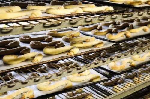 Freshly baked pretzels cooling on racks in a bakery, arranged in neat rows.