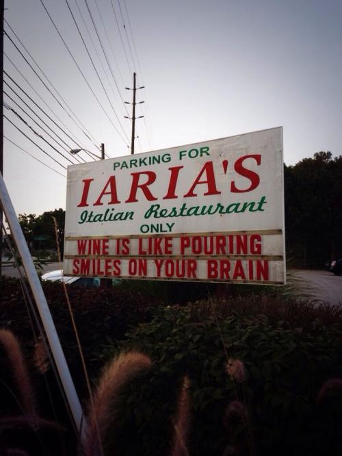 Sign for Iaria's Italian Restaurant with the message: "Wine is like pouring smiles on your brain." Parking information included.