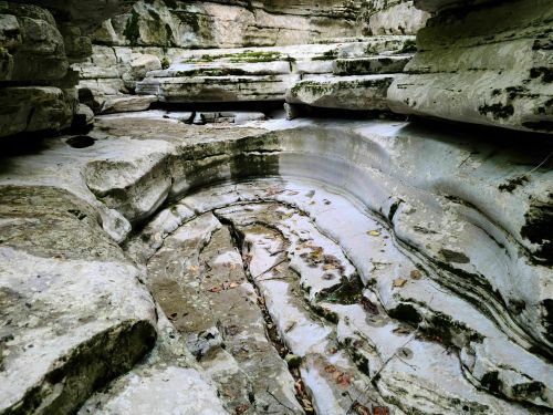 A rocky landscape with layered stone formations and a small stream running through the crevices.