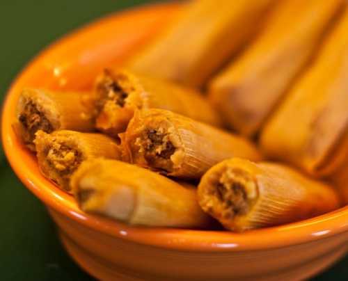 A bowl filled with tamales, showcasing their corn husk wrapping and savory filling.