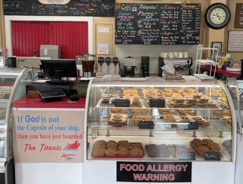 A bakery display case filled with cookies, featuring a sign about food allergies and a humorous Titanic quote.