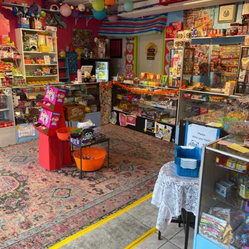 A colorful candy shop interior with shelves of sweets, a patterned rug, and a cozy seating area.