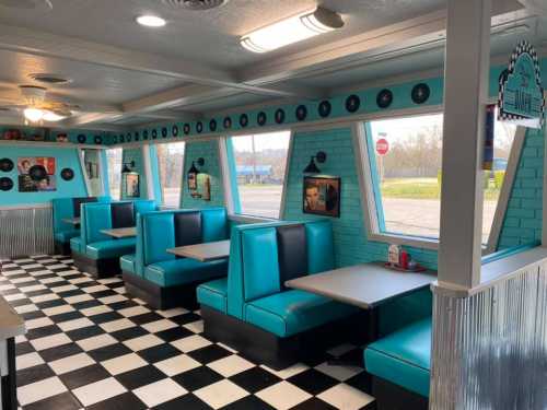 A retro diner interior with teal booths, checkered floor, and large windows, featuring vintage decor and a cozy atmosphere.