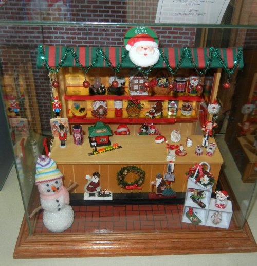 A festive display case featuring holiday decorations, a snowman, and various Christmas-themed figurines and ornaments.