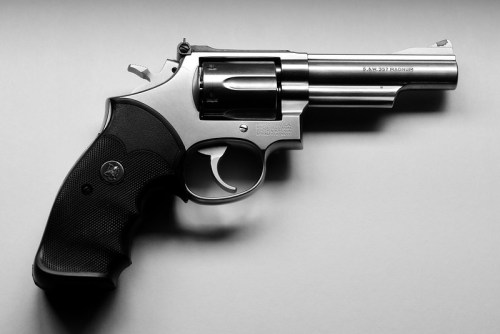 A silver revolver with a black grip, positioned on a light background.