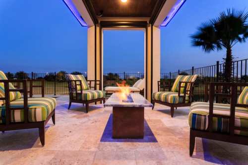 Cozy outdoor seating area with striped chairs around a fire pit, set against a twilight sky.