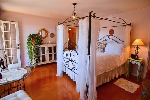 Cozy bedroom with a four-poster bed, soft lighting, and elegant decor, featuring a plant and vintage furniture.