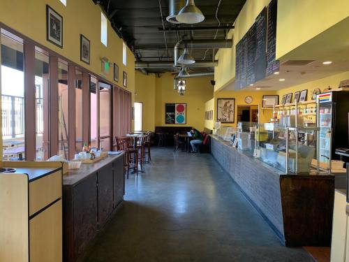 Interior of a café with yellow walls, wooden furniture, and a display counter, featuring a cozy and inviting atmosphere.