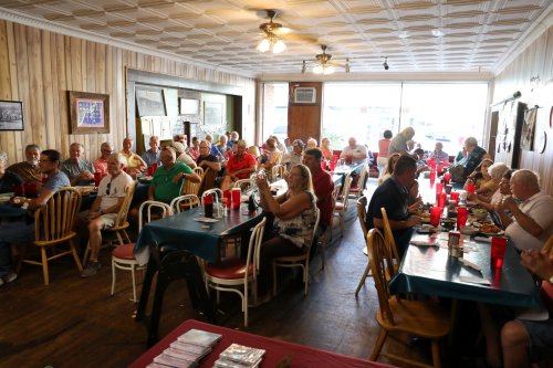 A bustling restaurant interior filled with diners at tables, enjoying meals and socializing in a cozy atmosphere.