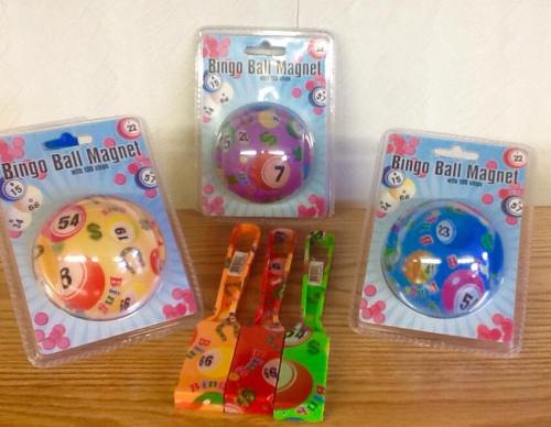 Three colorful bingo ball magnets in packaging, with five plastic bingo markers in various colors laid out in front.