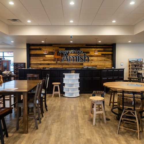 Interior of a rustic furniture store with wooden tables, chairs, and a sign reading "Everything Amish."