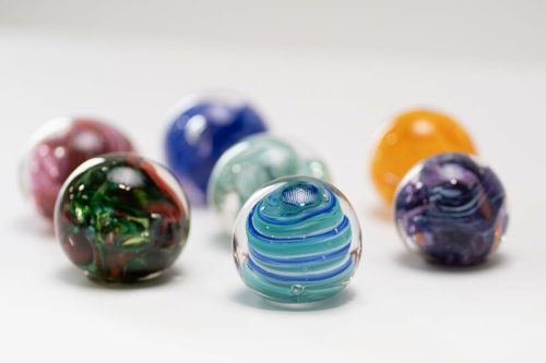 A collection of colorful glass marbles with swirling patterns, arranged on a light background.