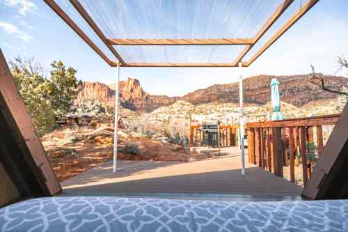 View from a deck overlooking rocky terrain and mountains, with a shaded area and outdoor seating.