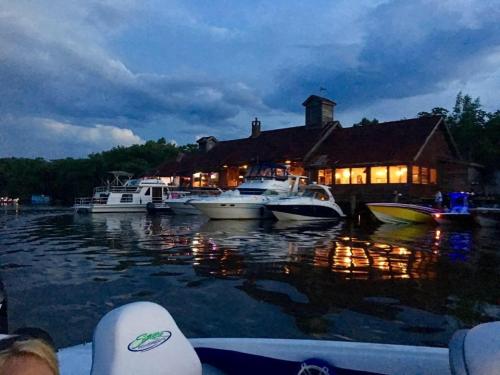 A serene evening scene of boats docked near a cozy waterfront restaurant, with dark clouds overhead.