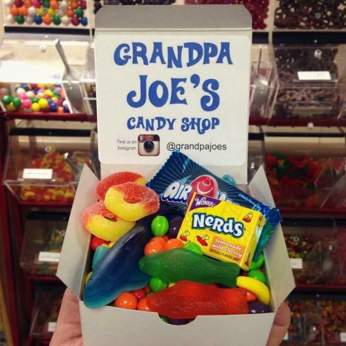 A colorful assortment of candies in a box from Grandpa Joe's Candy Shop, featuring gummies and Nerds.