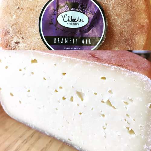 A block of cheese with a smooth texture, labeled "Brambly Ayr" from Elderslie Creamery, on a wooden surface.