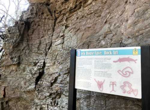 Rock House Cave features ancient rock art and an informational sign about its historical significance.