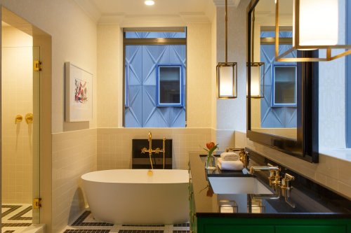 Modern bathroom featuring a freestanding tub, stylish fixtures, and a large window with city views.