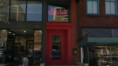 A storefront with a red door and a neon sign reading "Point" above it, located in a brick building.