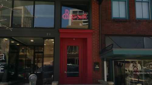 A storefront with a red door and a neon sign reading "Point" above it, located in a brick building.