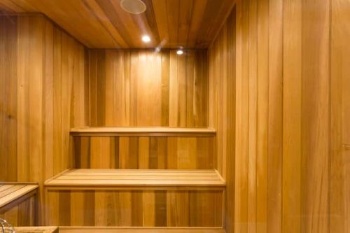 Interior of a wooden sauna with benches and soft lighting, featuring warm, natural wood paneling.