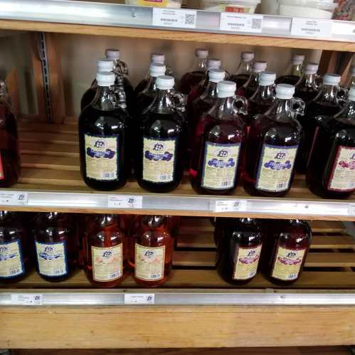 Shelves displaying various bottles of dark liquid, labeled with different colors and designs.