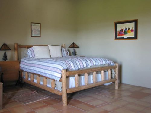 A cozy bedroom featuring a wooden bed, striped bedding, two lamps, and artwork on the wall.