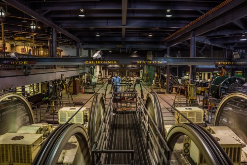 A view of an industrial facility with large machinery and a worker in blue, surrounded by equipment and structures.
