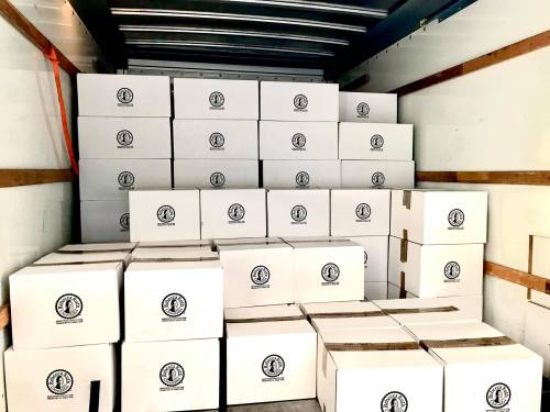 A truck interior filled with neatly stacked white boxes, all featuring a logo on the front.