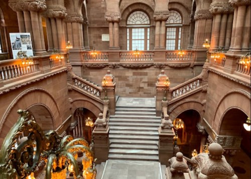 Elegant staircase in a grand building, featuring ornate architecture and warm lighting.