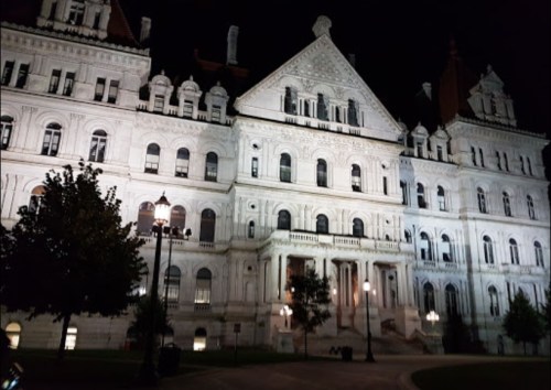 Illuminated historic building at night, showcasing intricate architecture and surrounding trees.