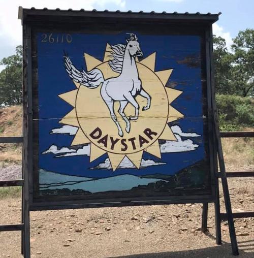 A colorful sign featuring a white horse rearing against a sunburst background, labeled "DAYSTAR."