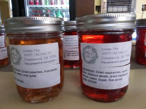Two jars of homemade fruit preserves with labels listing ingredients and contact information.