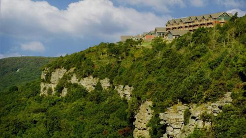 A hillside with lush greenery and a large building perched on top, under a partly cloudy sky.