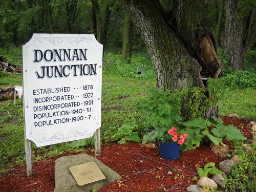Sign for Donnan Junction with historical details, surrounded by greenery and flowers.