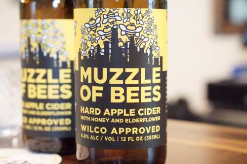 Label of "Muzzle of Bees" hard apple cider featuring honey and elderflower, with a city skyline design.
