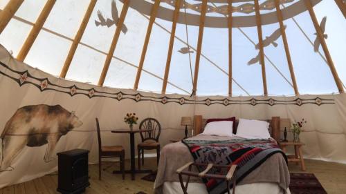 Cozy interior of a yurt with a bed, table, and decorative elements, featuring animal motifs on the walls.