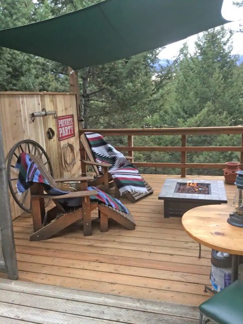 Cozy outdoor seating area with two chairs, a fire pit, and a "Private Party" sign, surrounded by trees.