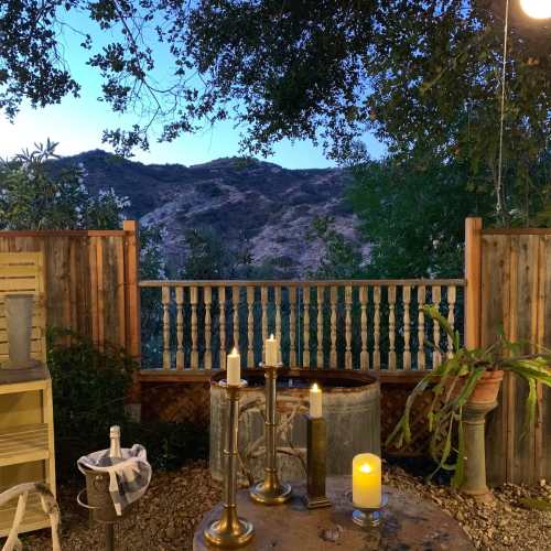 A serene outdoor setting with a wooden table, candles, and a view of mountains under a twilight sky.