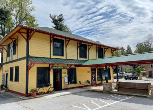 A yellow two-story building with a green roof, featuring a sign for the "Saddle Winter Center" and a bicycle outside.