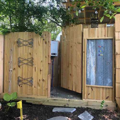 A wooden fence with decorative elements surrounds a small entrance, leading to a cozy outdoor space.