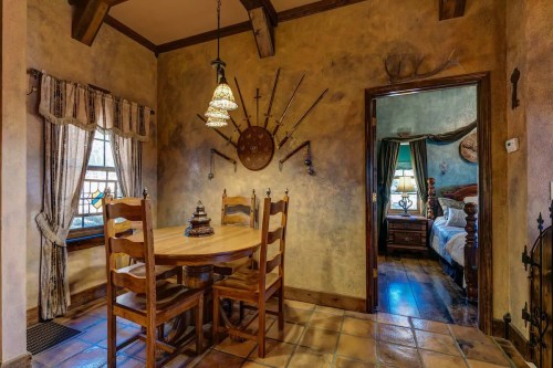 Cozy dining area with a wooden table and chairs, rustic decor, and a doorway leading to a bedroom.
