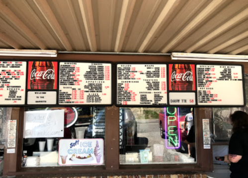 Menu board at a food stand featuring various items, including drinks, salads, and desserts, with prices listed.