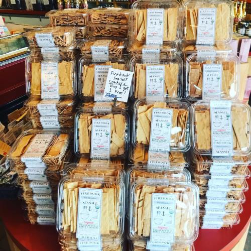 A display of stacked containers filled with sesame snacks, labeled and arranged in a store.