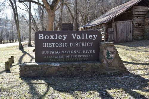Sign for Boxley Valley Historic District at Buffalo National River, with a rustic building in the background.