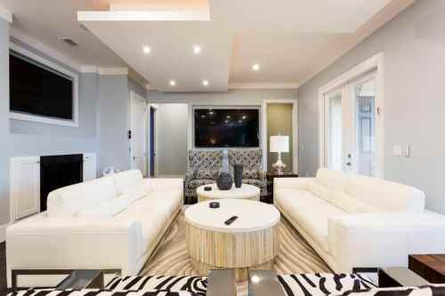 Modern living room featuring white sofas, a round coffee table, and a large TV against a stylish backdrop.