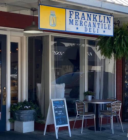 Exterior of Franklin Mercantile Deli, featuring a sign, outdoor seating, and a chalkboard menu.