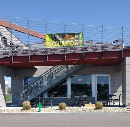 A restaurant exterior with a sign reading "El Columpio" and an open entrance, featuring stairs and outdoor seating.
