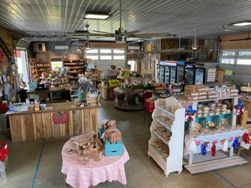 A spacious market interior with wooden displays, shelves of goods, and a variety of baked items on tables.