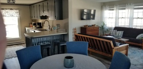 A cozy living space featuring a kitchen, dining table, and a comfortable seating area with natural light.